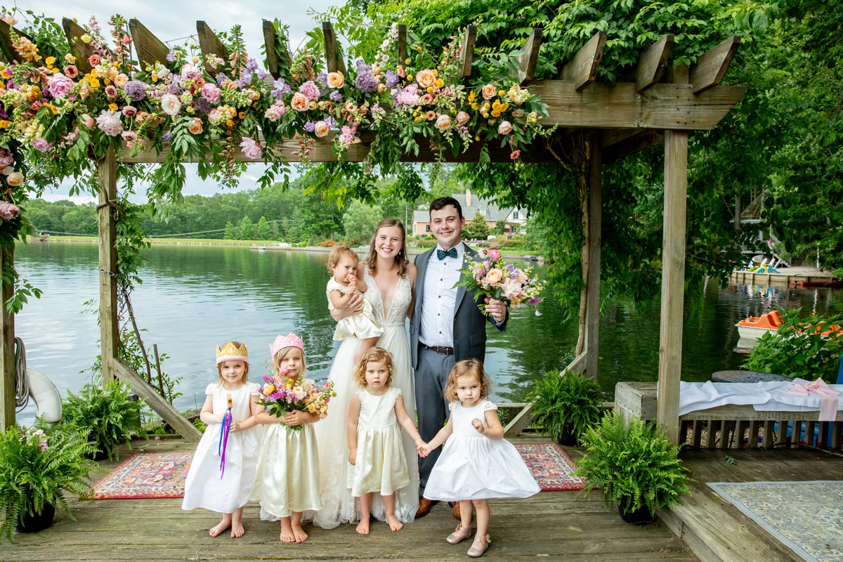 bride and groom with five flower girls on lake dock